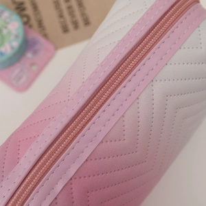 Close-up of pink gradient PU leather cosmetic bag with chevron perforated texture and zipper