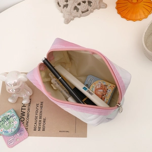 Flat lay of gradient pink quilted PU pouch with pens and stationery on a desk
