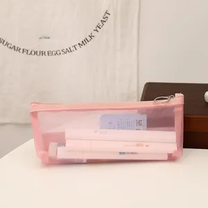 Detailed close-up of a pink mesh pencil case with metal zipper and stationery inside
