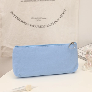 Close-up of light blue canvas pencil case with smooth zipper and silver metal pull ring