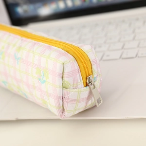 Close-up of quilted floral pencil case with yellow zipper on a white laptop keyboard