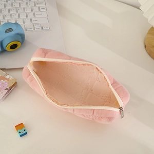 Detailed view of pink quilted plush pencil case with zipper closure on a desk