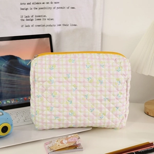 Detailed shot of quilted floral makeup bag with yellow zipper on a cozy desktop setup