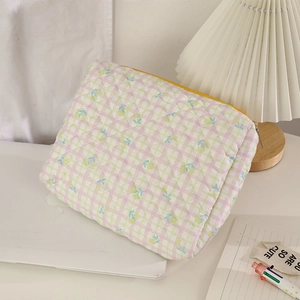 Macro view of floral quilted fabric makeup bag showing delicate stitching and zipper detail