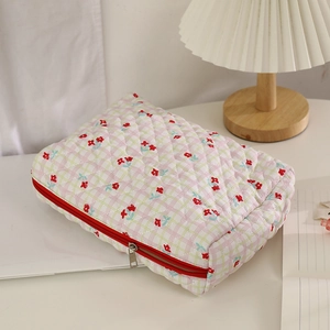 Quilted floral makeup bag with red zipper and vintage flower pattern on a white desk