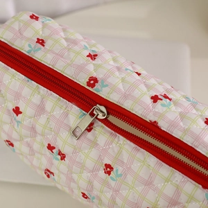 Detail of quilted floral pouch featuring red zipper and vintage plaid fabric texture
