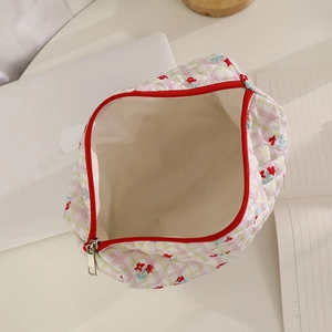 Quilted floral makeup bag with red flower patterns and zipper detail on a desk