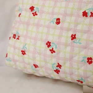 Detail of diamond quilted floral makeup bag with red flower pattern on checkered fabric