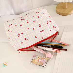 Detailed interior of floral quilted makeup bag with stationery items and red zipper