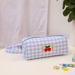 Dettaglio dell'astuccio a scacchi blu con toppa ciliegia e manico laterale