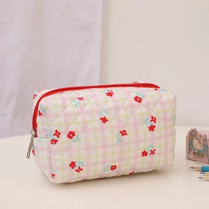 Close-up of quilted floral cosmetic bag with pink and green plaid pattern and red zipper