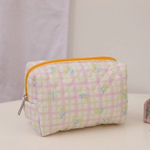 Close-up of quilted floral cosmetic bag with yellow zipper and pastel plaid pattern