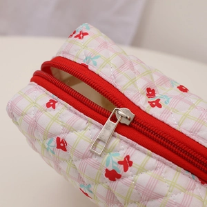 Detail of quilted floral pouch with red zipper and silver metal puller on plaid cotton