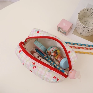 Close-up of quilted floral pencil case with red zipper and cute pink cartoon charm detail