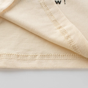 Détail d'un t-shirt à manches longues pour garçon en maille crème avec finitions soignées