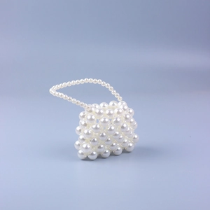 Detail of white faux pearl woven mini bag with elegant handmade beaded texture