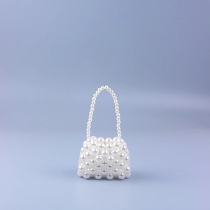 Close-up of elegant mini faux pearl beaded handbag with woven texture and top handle