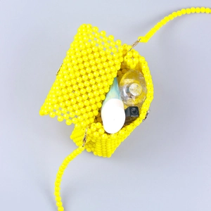 Detailed view of yellow beaded crossbody bag interior showing storage capacity for cosmetics