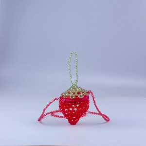 Detailed view of red acrylic strawberry-shaped beaded bag with green leaf top