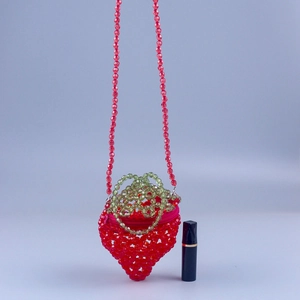 Macro detail of a handmade strawberry beaded mini bag with pearls and zipper closure