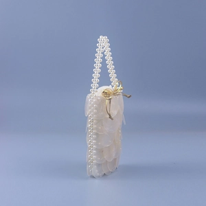 Detail of white fish-scale sequins and handmade pearl beads on shell shaped handbag