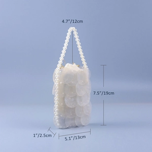 Detailed view of pearl handle and shell-like sequins on a handmade beaded bag with dimensions