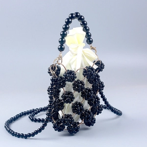 Detail of handmade black acrylic beaded handbag with golden rings and satin drawstring pouch