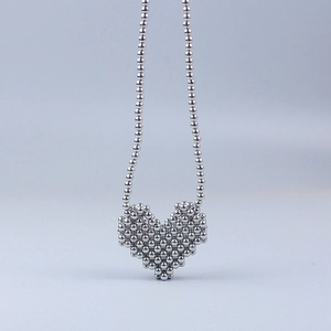 Dettaglio del ciondolo a cuore 3D in sfere d'argento con catena di perle abbinata