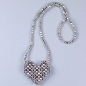 Dettaglio macro della collana di perle d'argento e del ciondolo a cuore lucido metallico