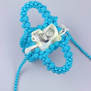Detail of bright blue beaded handbag with white satin lining and long crossbody strap