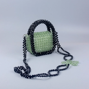 Detail of handmade green acrylic beaded mini bag with floral cutouts and crossbody strap