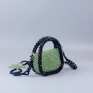 Detail of hand-woven green acrylic beads with black edging on a mini handbag