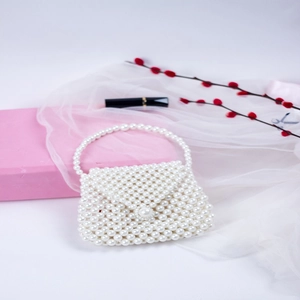 Detail of hand-woven pearl dumpling bag showing white glossy beads and elegant handle