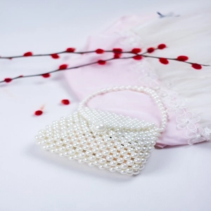 Detail of handmade faux pearl beaded handbag with elegant top handle and flap closure