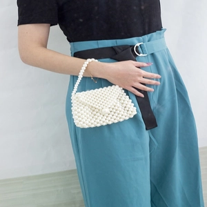 Detail of elegant handmade faux pearl beaded handbag with white woven structure