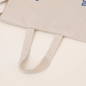 Detail of reinforced stitching and blue print on beige Oxford canvas file bag