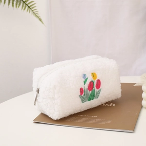 Detail of white sherpa makeup bag featuring delicate tulip embroidery and silver zipper