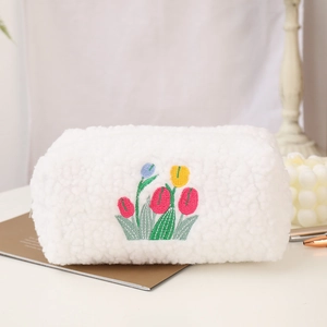 Close-up of white plush cosmetic bag with elegant tulip flower embroidery and soft texture