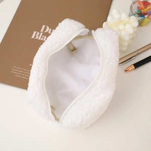 Detail of white sherpa fleece makeup bag with cute ears and zipper on a desk