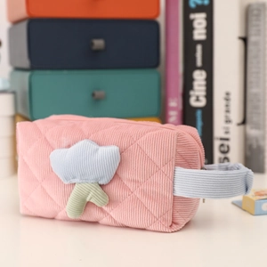Detail of pink corduroy makeup bag featuring quilted texture and blue floral patch