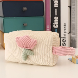 Close-up of cream corduroy makeup bag featuring pink tulip embroidery and quilted texture