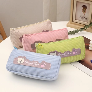 Detail of corduroy pencil cases in four pastel colors with bear labels and metal rings