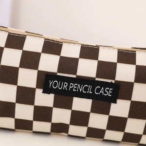 Macro shot of canvas checkerboard pencil case showing the fabric texture and logo label