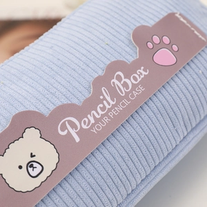 Close-up of light blue corduroy pencil case texture and cartoon bear decorative label