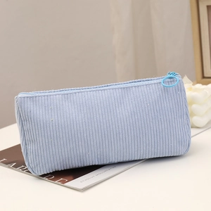 Detail of light blue corduroy pencil case with a round pull ring zipper on a magazine
