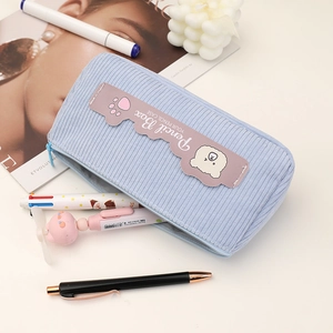 Close-up of light blue corduroy pencil case with bear patch and smooth zipper detail