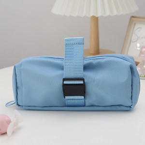 Close-up of light blue nylon pencil case with buckle strap in a cozy desk setting
