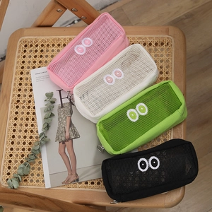 Detail of four colorful mesh pencil cases with big eye embroidery on a wooden chair