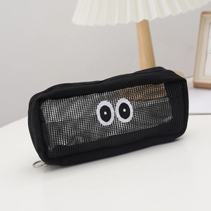 Black mesh pencil case with big eye embroidery on desk with lamp and wood frame