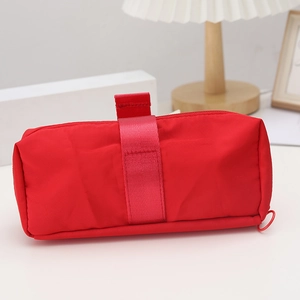 Detailed view of red nylon pencil case with wide ribbon trim and top carry handle